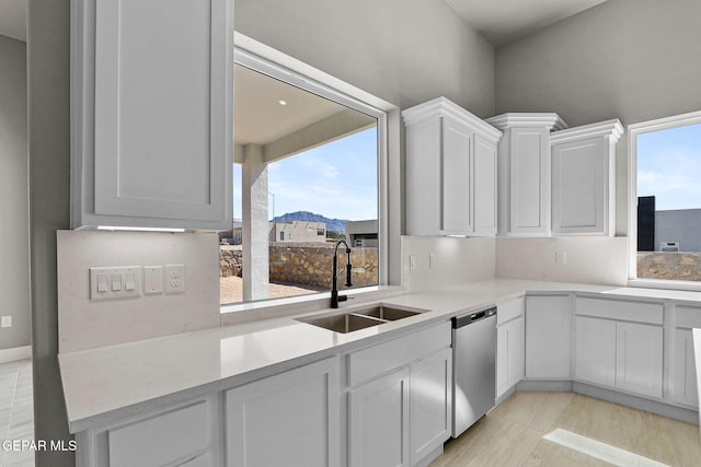 kitchen with tasteful backsplash, white cabinets, sink, and dishwasher