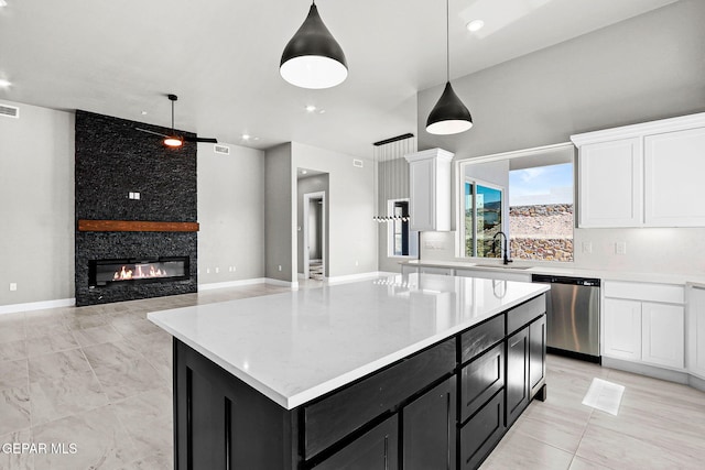 kitchen with a stone fireplace, stainless steel dishwasher, hanging light fixtures, white cabinets, and a center island