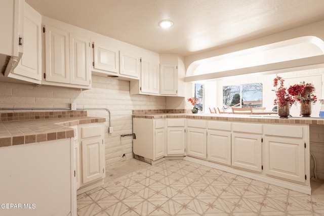 kitchen with tile counters, white cabinetry, and light tile floors