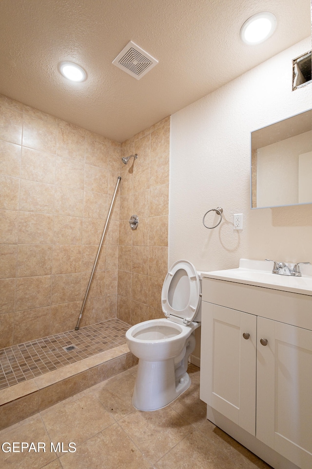 bathroom with tile floors, a textured ceiling, vanity, and toilet