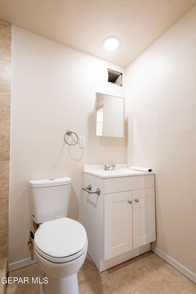 bathroom with tile flooring, a textured ceiling, toilet, and vanity