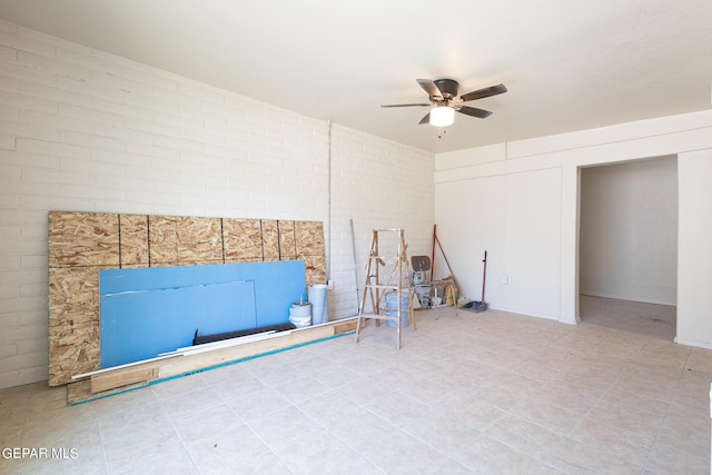 interior space with brick wall, ceiling fan, and tile floors