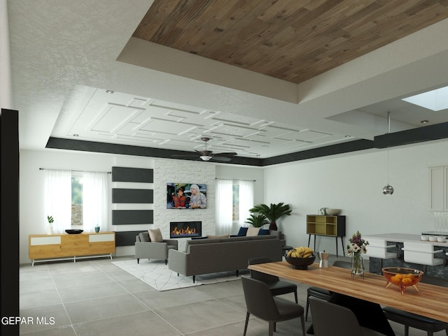 interior space with a tray ceiling, a fireplace, wooden ceiling, and ceiling fan