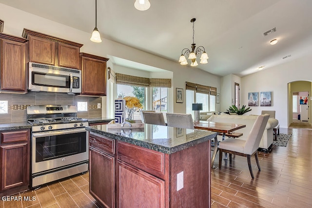 kitchen with pendant lighting, appliances with stainless steel finishes, backsplash, dark hardwood / wood-style floors, and an inviting chandelier