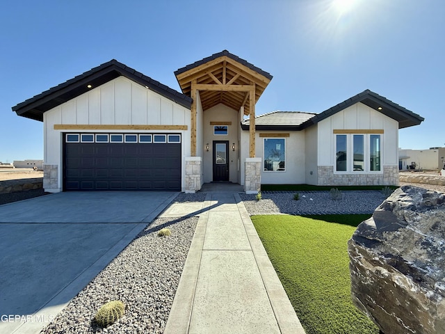 view of front facade featuring a tile roof, stone siding, board and batten siding, concrete driveway, and a garage