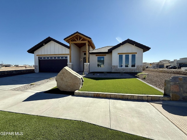 view of front facade with stone siding, board and batten siding, concrete driveway, a front yard, and a garage