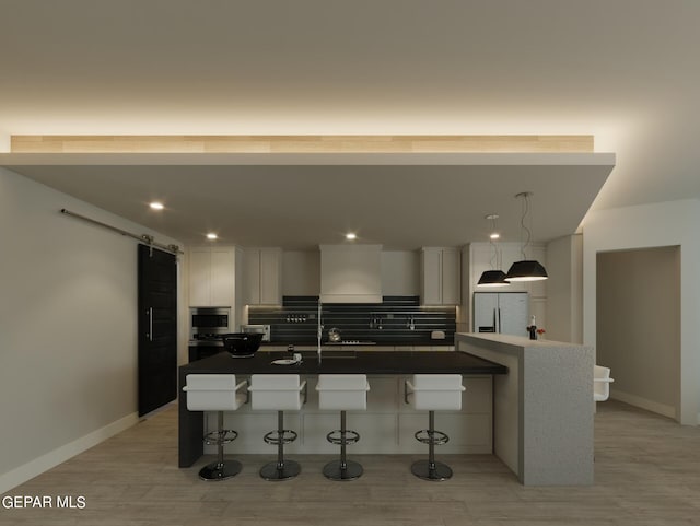 kitchen with light hardwood / wood-style flooring, a breakfast bar, stainless steel refrigerator with ice dispenser, decorative backsplash, and a barn door