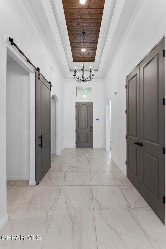 foyer entrance featuring a raised ceiling, a barn door, an inviting chandelier, and wood ceiling