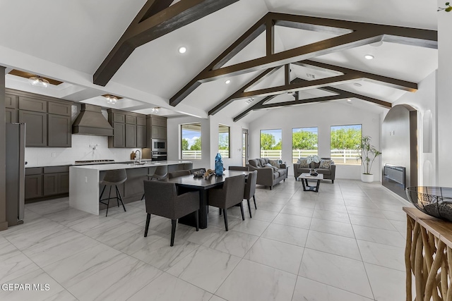 dining area featuring beam ceiling, sink, and high vaulted ceiling