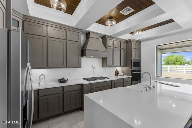 kitchen featuring a raised ceiling, appliances with stainless steel finishes, wooden ceiling, and custom exhaust hood