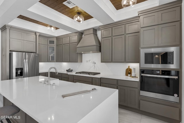 kitchen with wood ceiling, backsplash, stainless steel appliances, and custom range hood