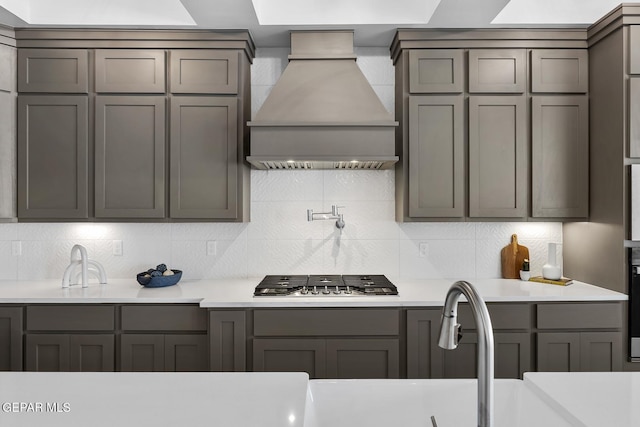 kitchen featuring premium range hood, tasteful backsplash, sink, gray cabinets, and stainless steel gas stovetop