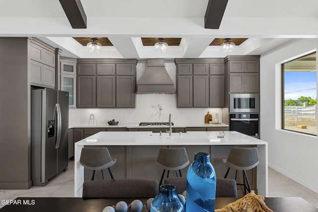 kitchen featuring premium range hood, a kitchen bar, decorative backsplash, a center island with sink, and appliances with stainless steel finishes