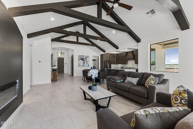 living room featuring beamed ceiling, ceiling fan with notable chandelier, and high vaulted ceiling