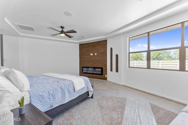 carpeted bedroom with ceiling fan and a fireplace