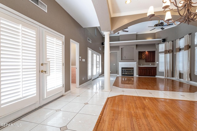 18 Via Placita, El Paso, TX 79927 - unfurnished living room featuring ceiling fan, light tile patterned floors, decorative columns, a glass covered fireplace, and crown molding