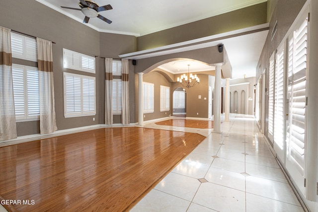 interior space featuring crown molding, plenty of natural light, light tile patterned floors, and ceiling fan with notable chandelier