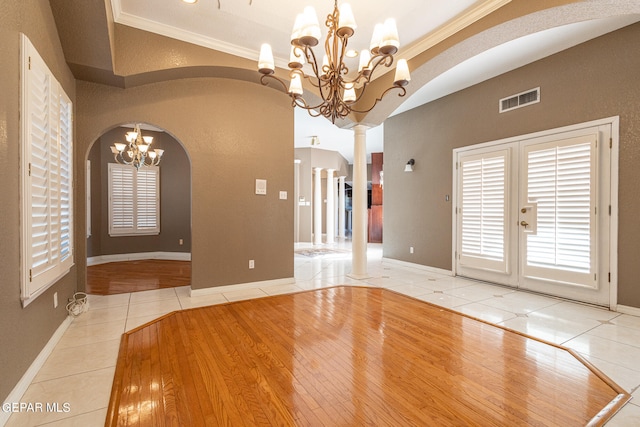 empty room with tile patterned flooring, a notable chandelier, and ornamental molding