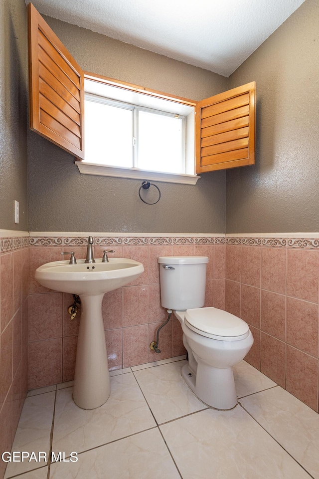 18 Via Placita, El Paso, TX 79927 - half bathroom with tile walls, toilet, a textured wall, and wainscoting
