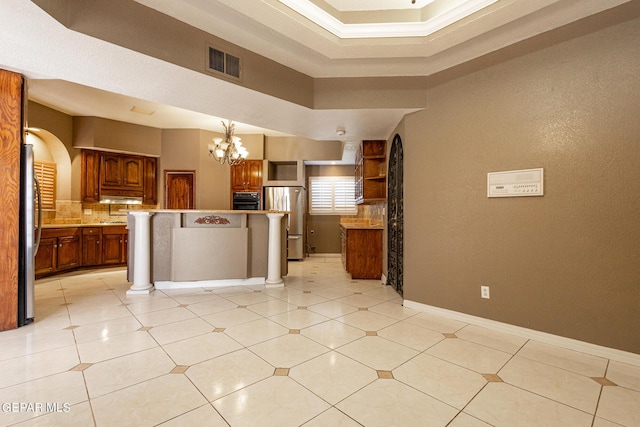 18 Via Placita, El Paso, TX 79927 - kitchen featuring freestanding refrigerator, decorative backsplash, a chandelier, brown cabinetry, and oven