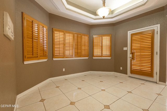 empty room featuring a raised ceiling and crown molding