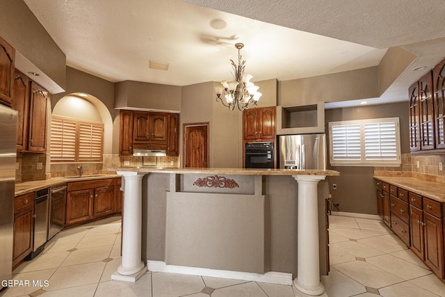 18 Via Placita, El Paso, TX 79927 - kitchen with stainless steel appliances, decorative backsplash, a center island, light tile patterned flooring, and decorative light fixtures