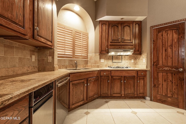 18 Via Placita, El Paso, TX 79927 - kitchen with appliances with stainless steel finishes, range hood, light countertops, tasteful backsplash, and light tile patterned floors
