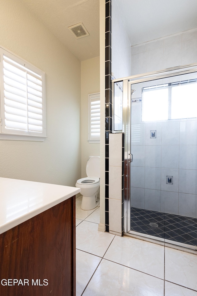 bathroom with tile patterned floors, vanity, toilet, and a shower with door