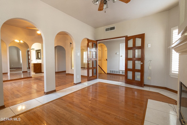 tiled entrance foyer with ceiling fan and french doors