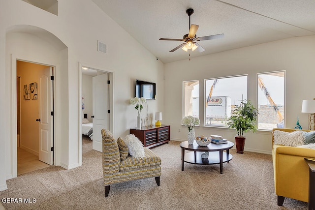 carpeted living room with ceiling fan, a textured ceiling, and lofted ceiling