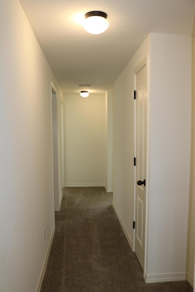 hallway featuring dark colored carpet