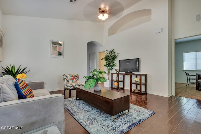 living room featuring high vaulted ceiling, ceiling fan, and dark wood-type flooring