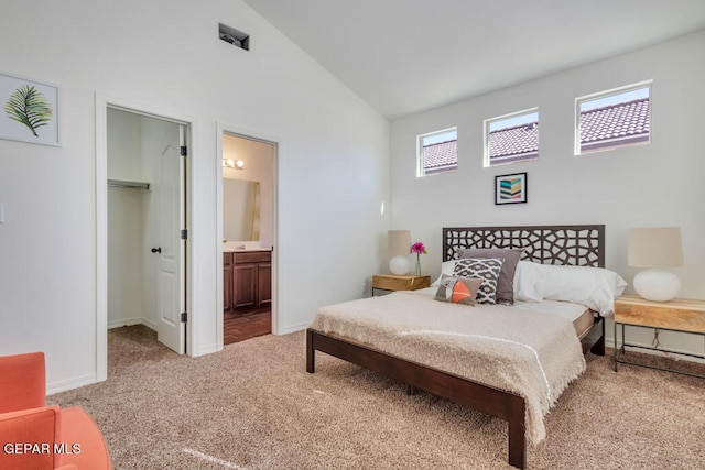 bedroom with high vaulted ceiling, a closet, connected bathroom, a spacious closet, and light colored carpet