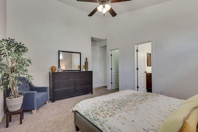 bedroom with light colored carpet, ceiling fan, ensuite bath, and a high ceiling