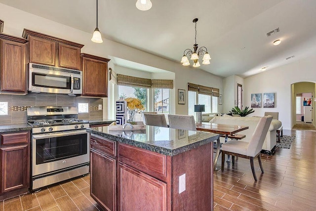 kitchen featuring backsplash, stainless steel appliances, a chandelier, and hanging light fixtures