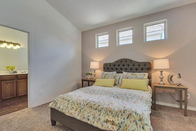 bedroom with vaulted ceiling, dark carpet, and ensuite bathroom