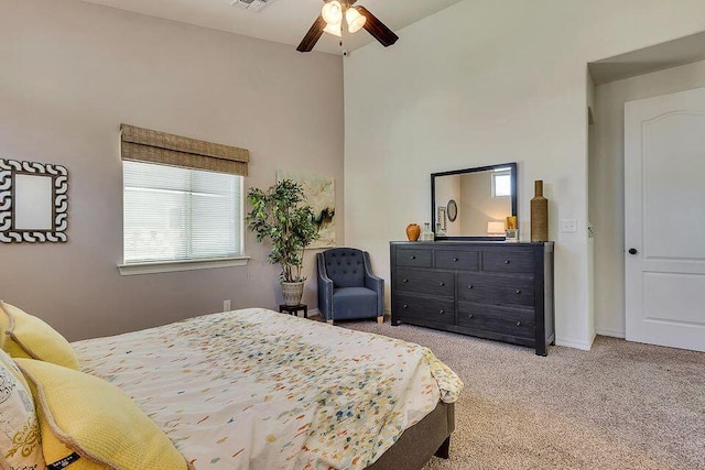 bedroom featuring light colored carpet, ceiling fan, a high ceiling, and multiple windows