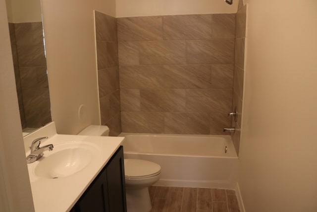 full bathroom featuring hardwood / wood-style floors, tiled shower / bath, vanity, and toilet