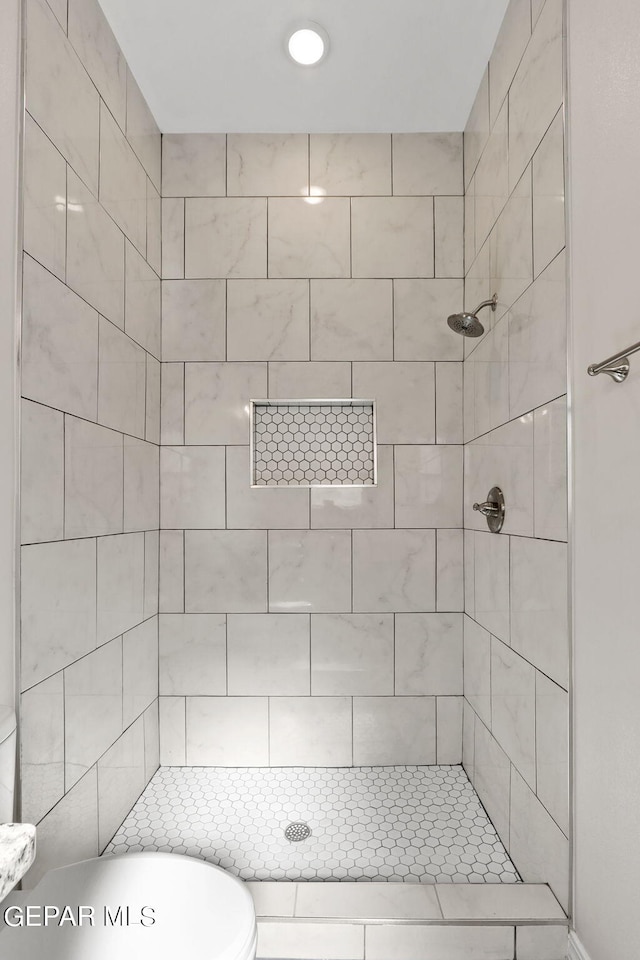 bathroom featuring toilet and a tile shower