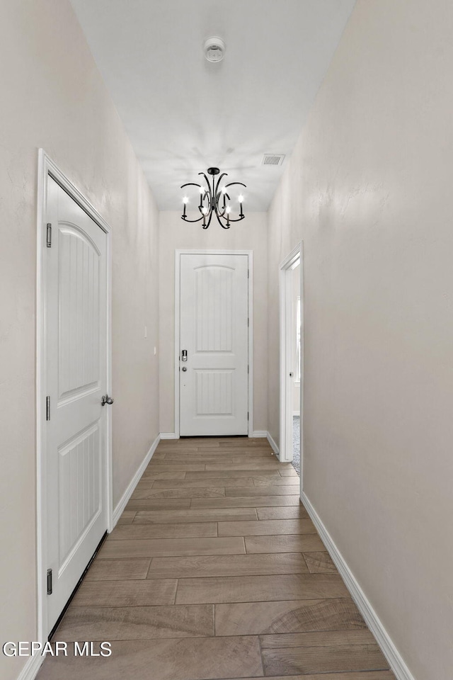 doorway to outside featuring a notable chandelier and light wood-type flooring