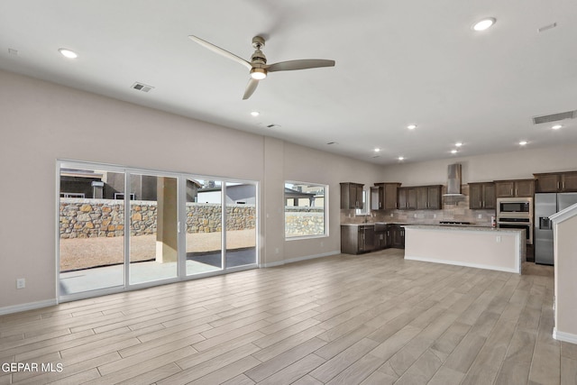 unfurnished living room with light hardwood / wood-style flooring, ceiling fan, and sink