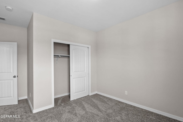 unfurnished bedroom featuring a closet and dark carpet