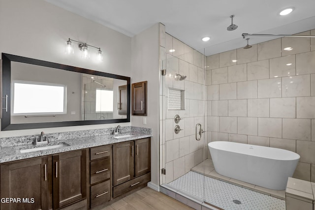 bathroom with tile walls, oversized vanity, tile flooring, double sink, and separate shower and tub