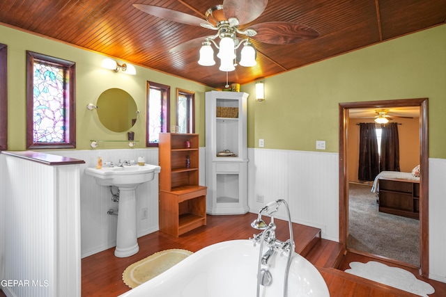 bathroom featuring wooden ceiling, hardwood / wood-style floors, ceiling fan, and a bathtub