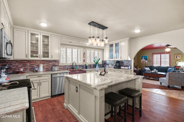 kitchen with appliances with stainless steel finishes, a center island, backsplash, and a wealth of natural light