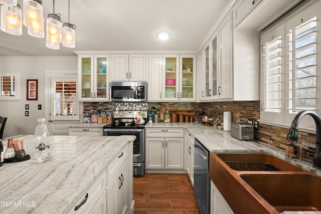 kitchen featuring backsplash, appliances with stainless steel finishes, white cabinets, and sink