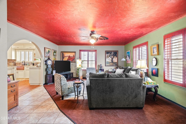 living room with ornamental molding, sink, ceiling fan, and light tile flooring