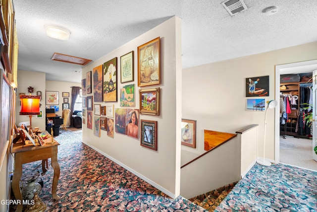 corridor featuring carpet flooring and a textured ceiling