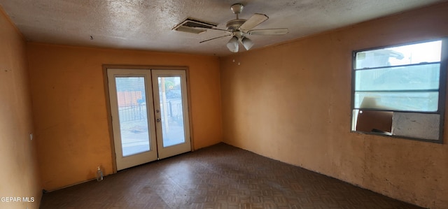 empty room with french doors, a textured ceiling, visible vents, and ceiling fan