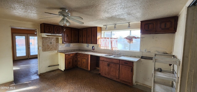 kitchen with under cabinet range hood, a healthy amount of sunlight, light countertops, and a sink